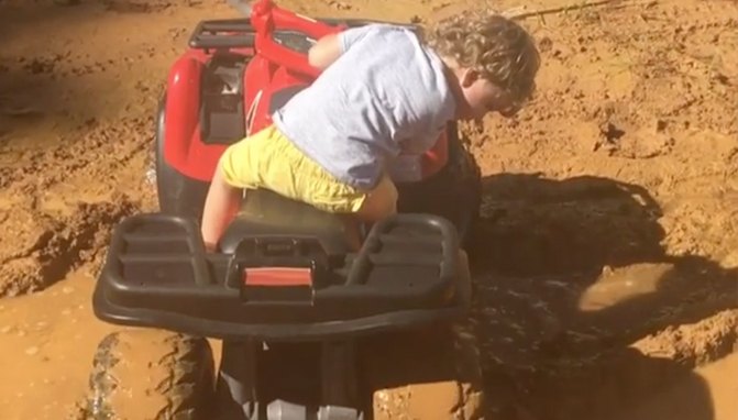 child takes battery powered atv through mud hole video