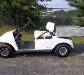 good looking club car electric golf cart that has a metal utility box mounted to