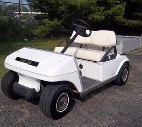 good looking club car electric golf cart that has a metal utility box mounted to